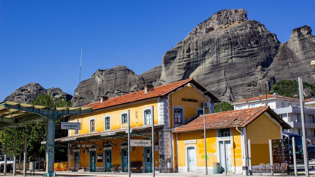 The yellow Kalambaka railway station with the Meteora rocks behind it