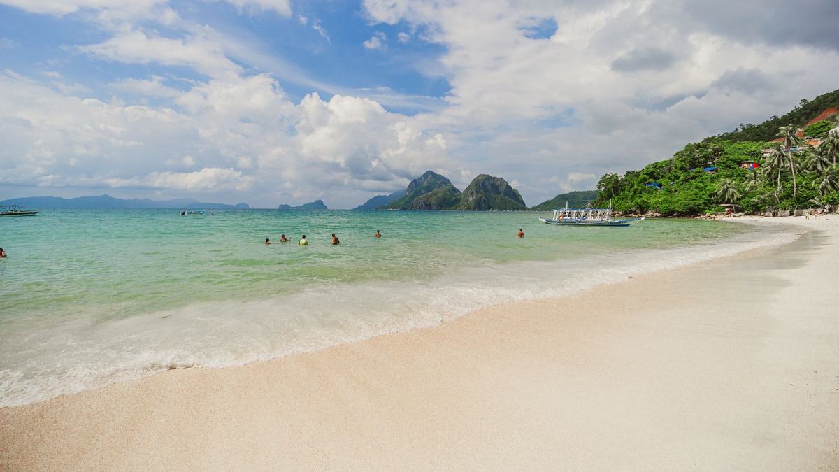 A calm turquoise sea off a white beach in Palawan