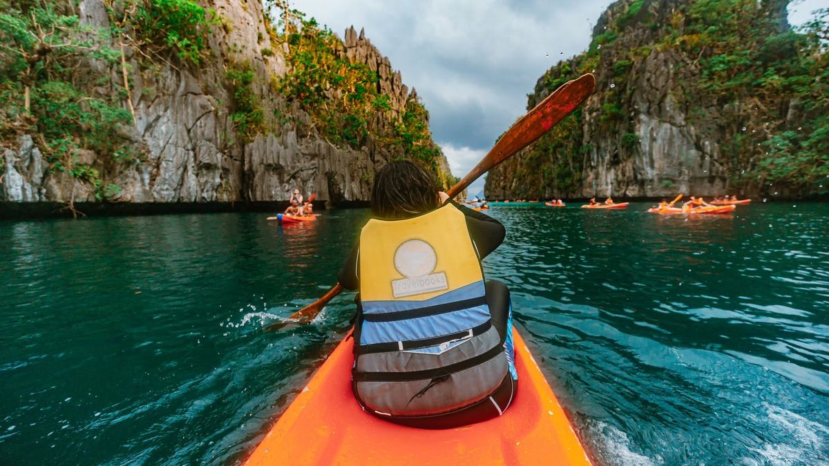 A kayaker paddling between limestone cliffs, seen from behind