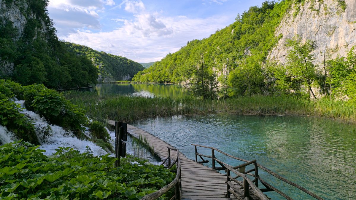 A family walking on a wooden boardwalk over clear water