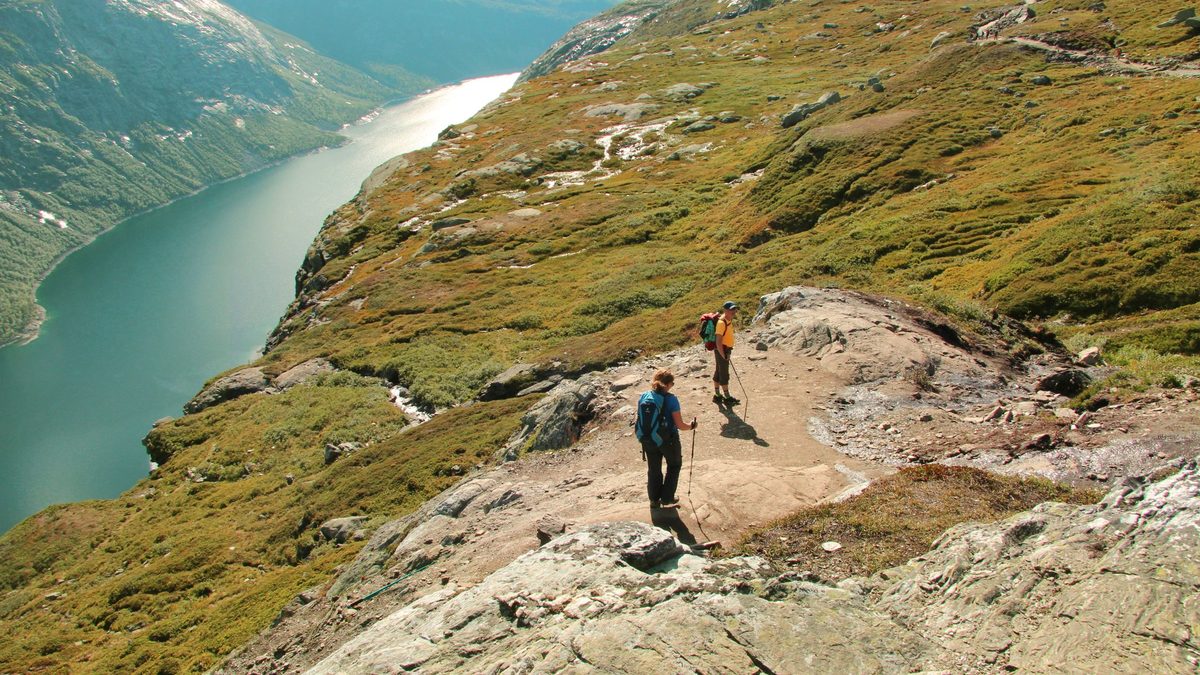 A hiker with a backpack on a rocky mountain trail in Norway